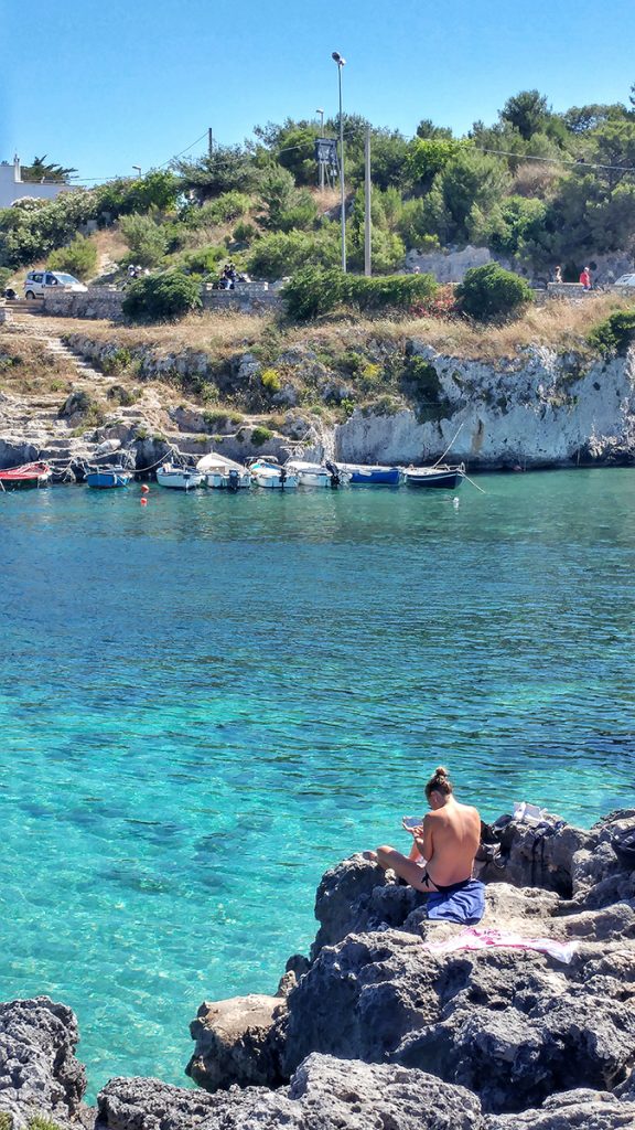 ragazza che prende il sole sugli scogli della baia di Porto Badisco