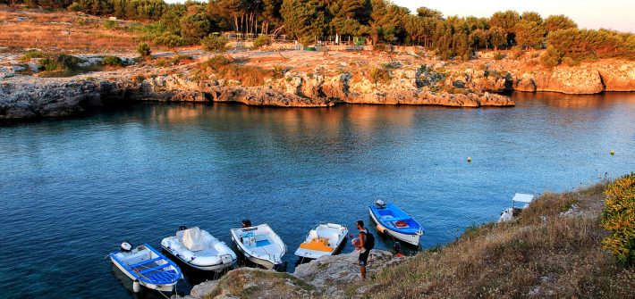 Delle barche legate sugli scogli di Porto Badisco al tramonto