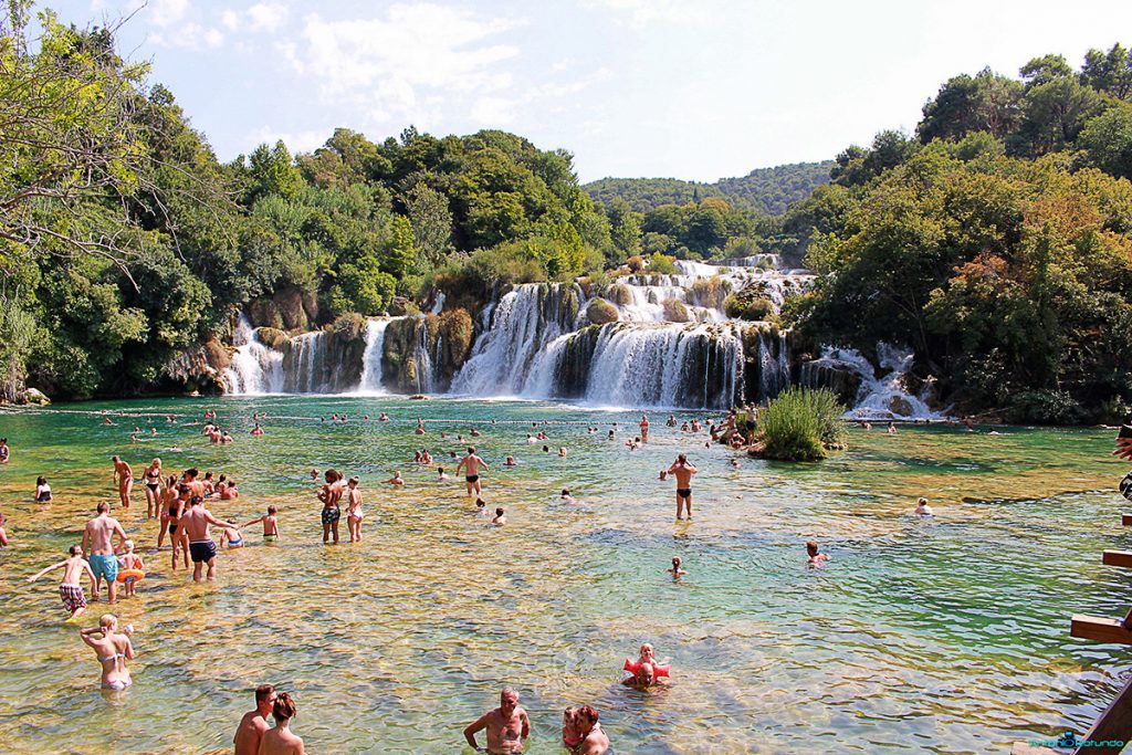 Persone che fanno il bagno sotto le cascate del parco di Krka