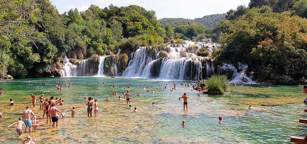 Persone che fanno il bagno sotto le cascate del parco di Krka