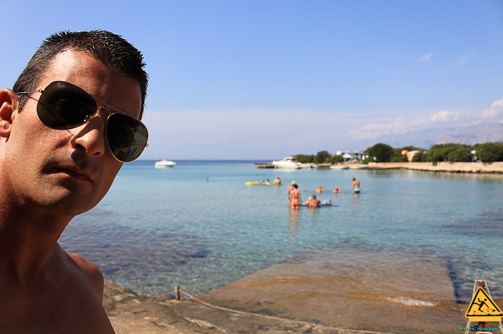 un mio selfie con alle spalle una caletta con dei ragazzi che fanno il bagno durante il mio viaggio in Croazia