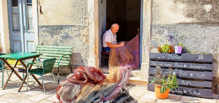 un pescatore conosciuto durante il mio viaggio in Croazia che ripara la sua rete da pesca