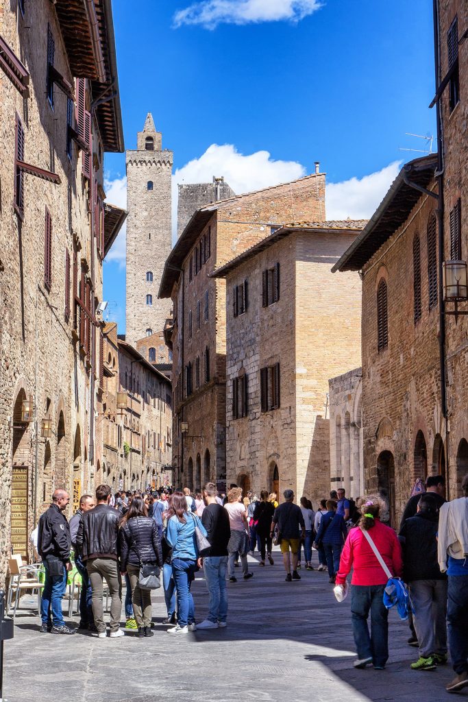 una strada del centro con persone che passeggiano, ecco cosa vedere a San Gimignano