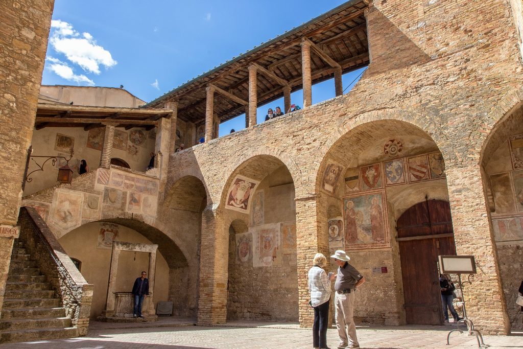 interno del cortile del Palazzo Comunale, con una cisterna sullo sfondo e una scala. Ecco cosa vedere a San Gimignano in piazza Duomo.