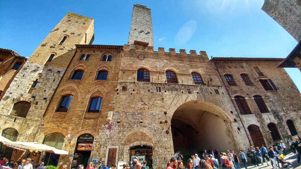un palazzo storico con un arco e una torre sulla sommità, ecco cosa vedere a San Gimignano