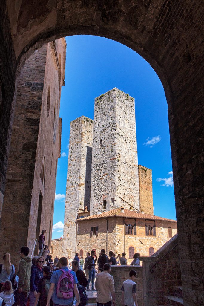 un arco con due torri medievali sullo sfondo, ecco cosa vedere a San Gimignano