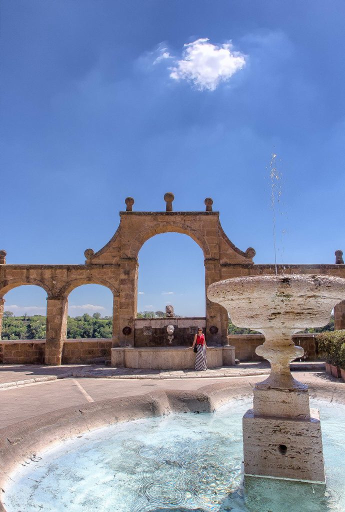 una fontana in primo piano con l'acquedotto di Pitigliano sullo sfondo, ecco cosa vedere in Maremma