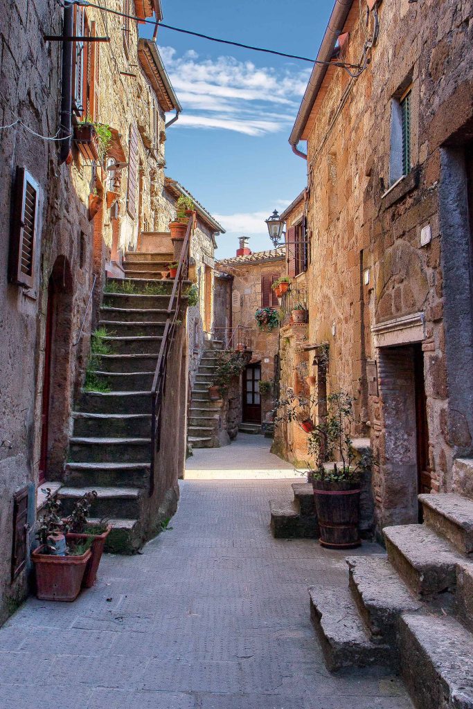 Un vicolo all'interno di Pitigliano pieno di vasi fioriti e piccole scalinate, ecco cosa vedere in maremma