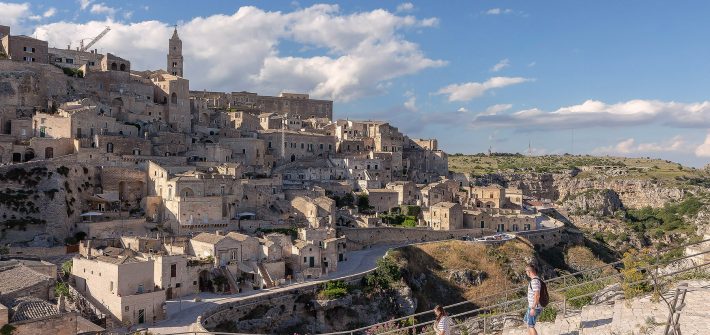 La città di Matera sullo sfondo e due ragazzi che scendono una scalinata in primo piano. Visitare Matera in un giorno